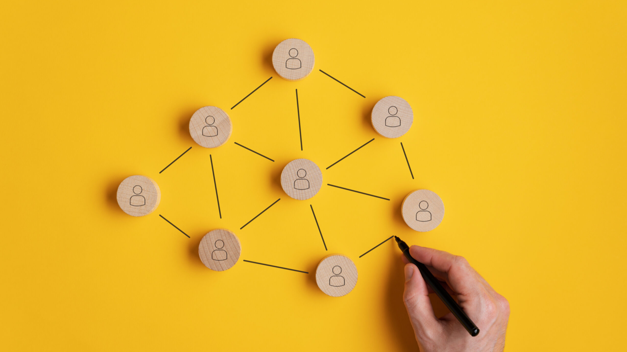 Image conceptuelle du marketing de réseau - main d'homme reliant les cercles découpés en bois avec icône de personne sur ceux-ci.