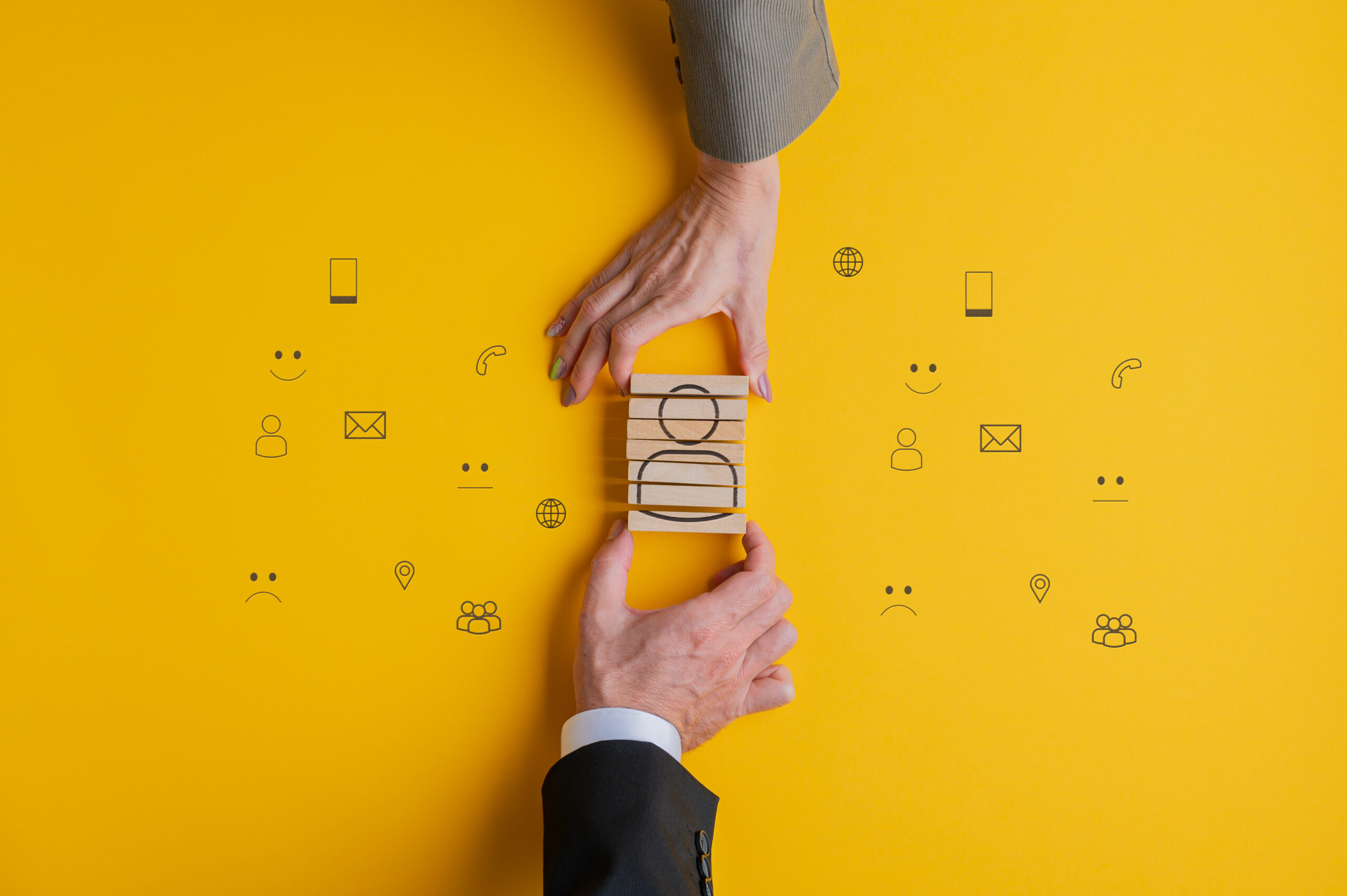 Customer service and support conceptual image - hands of business partners assembling a people icon on wooden blocks.